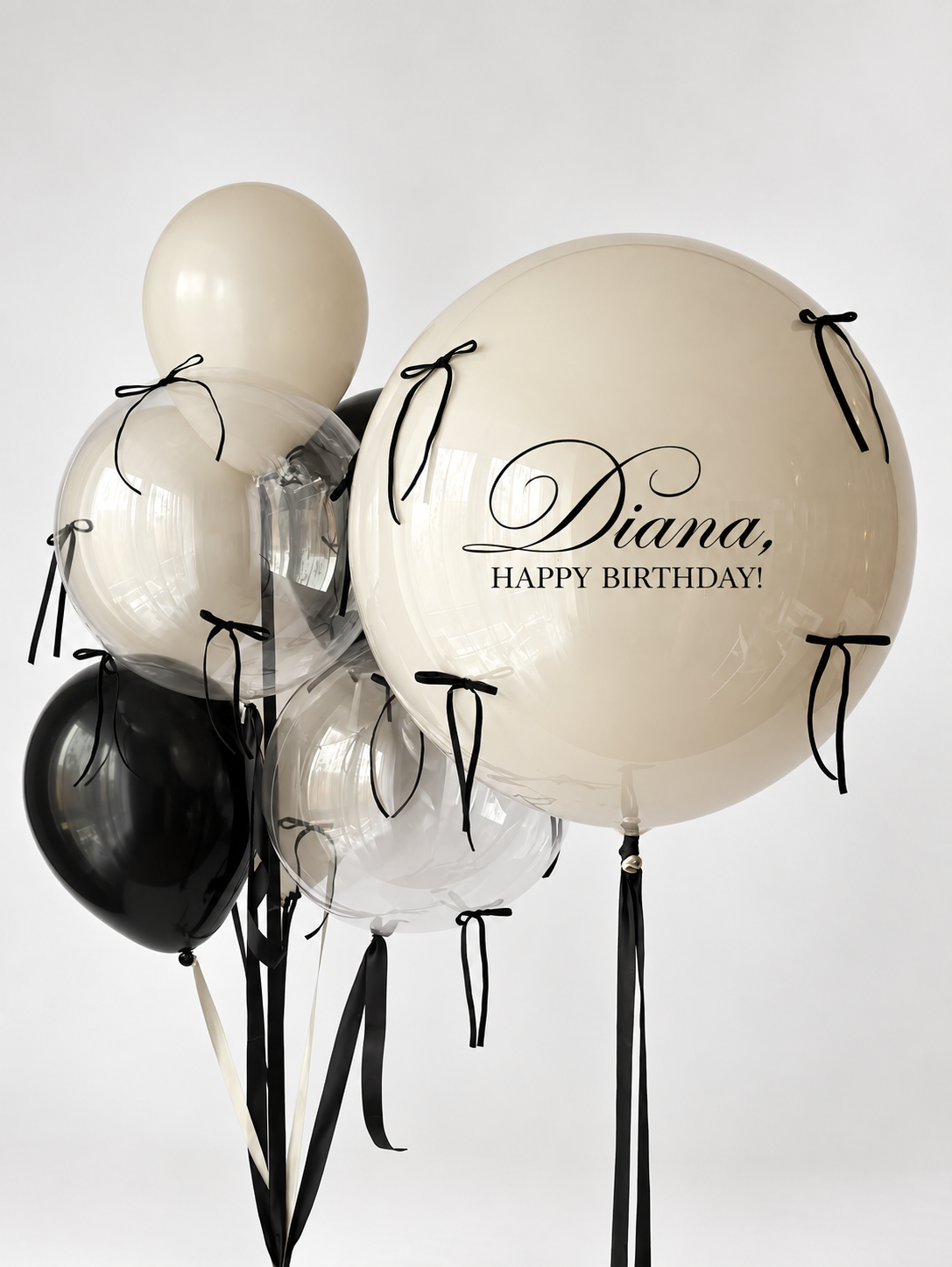 Large personalized cream bubble balloon with black bows, two smaller clear bubble balloons and coordinating black and cream balloons.