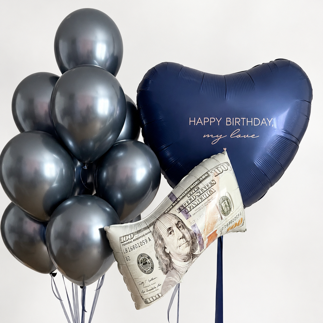 Personalized navy heart balloon with birthday lettering, a foil balloon shaped like a 100-dollar bill, and a bunch of metallic charcoal gray latex balloons.
