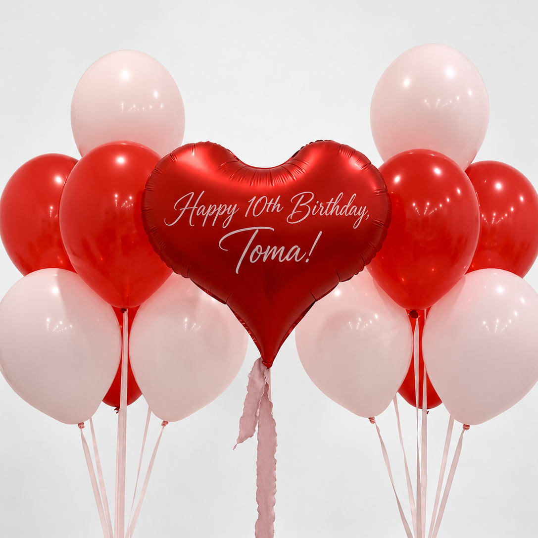 Red heart balloon with a personalized birthday message between two bunches of red and pale pink latex balloons with pink ribbons.