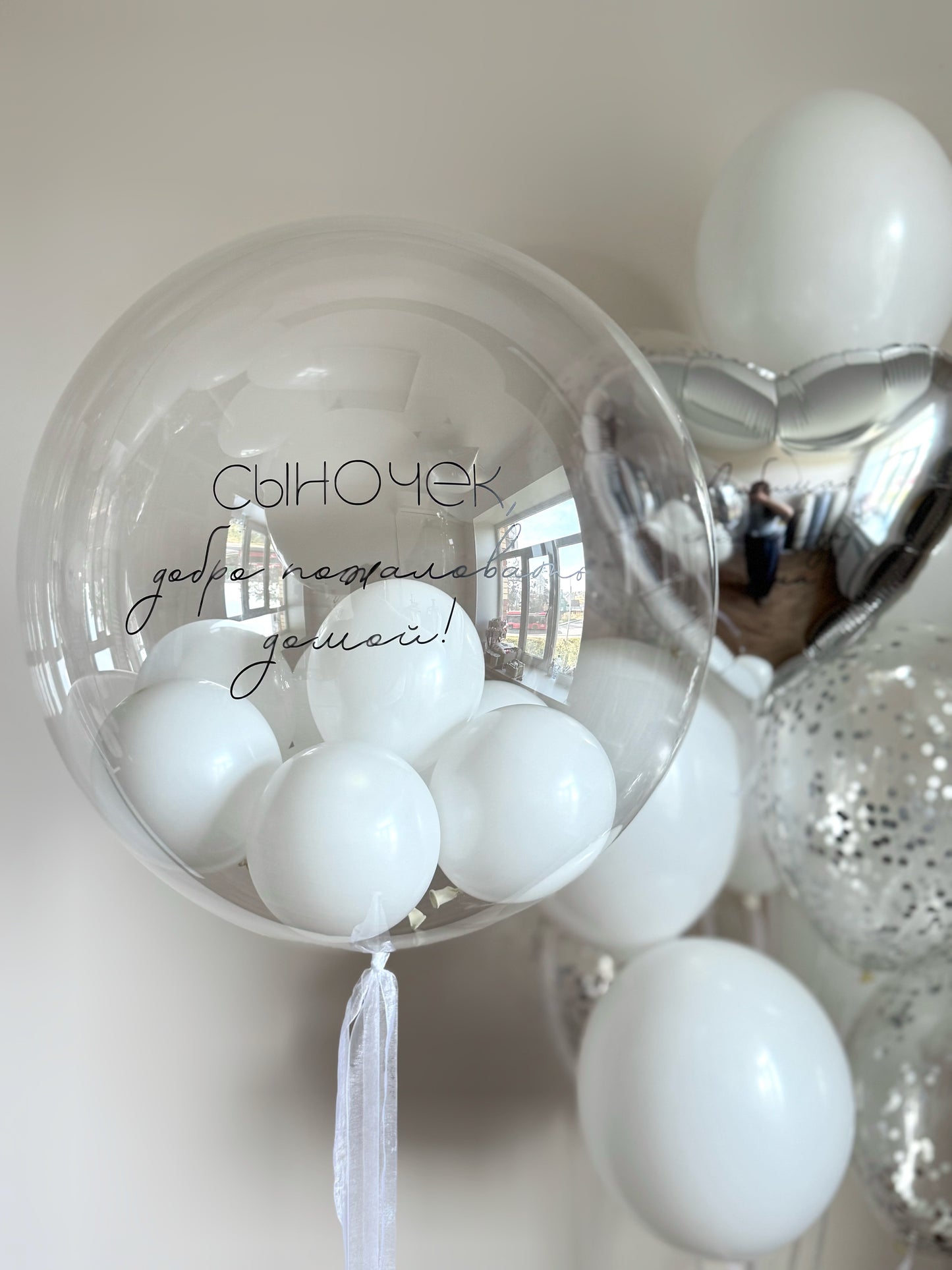 Close-up of modern welcome bubble balloon arrangement with custom sign and white balloons in NYC