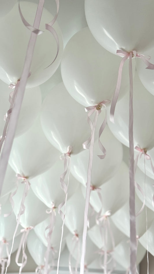 White helium ceiling balloons with pink ribbon bows in New York City
