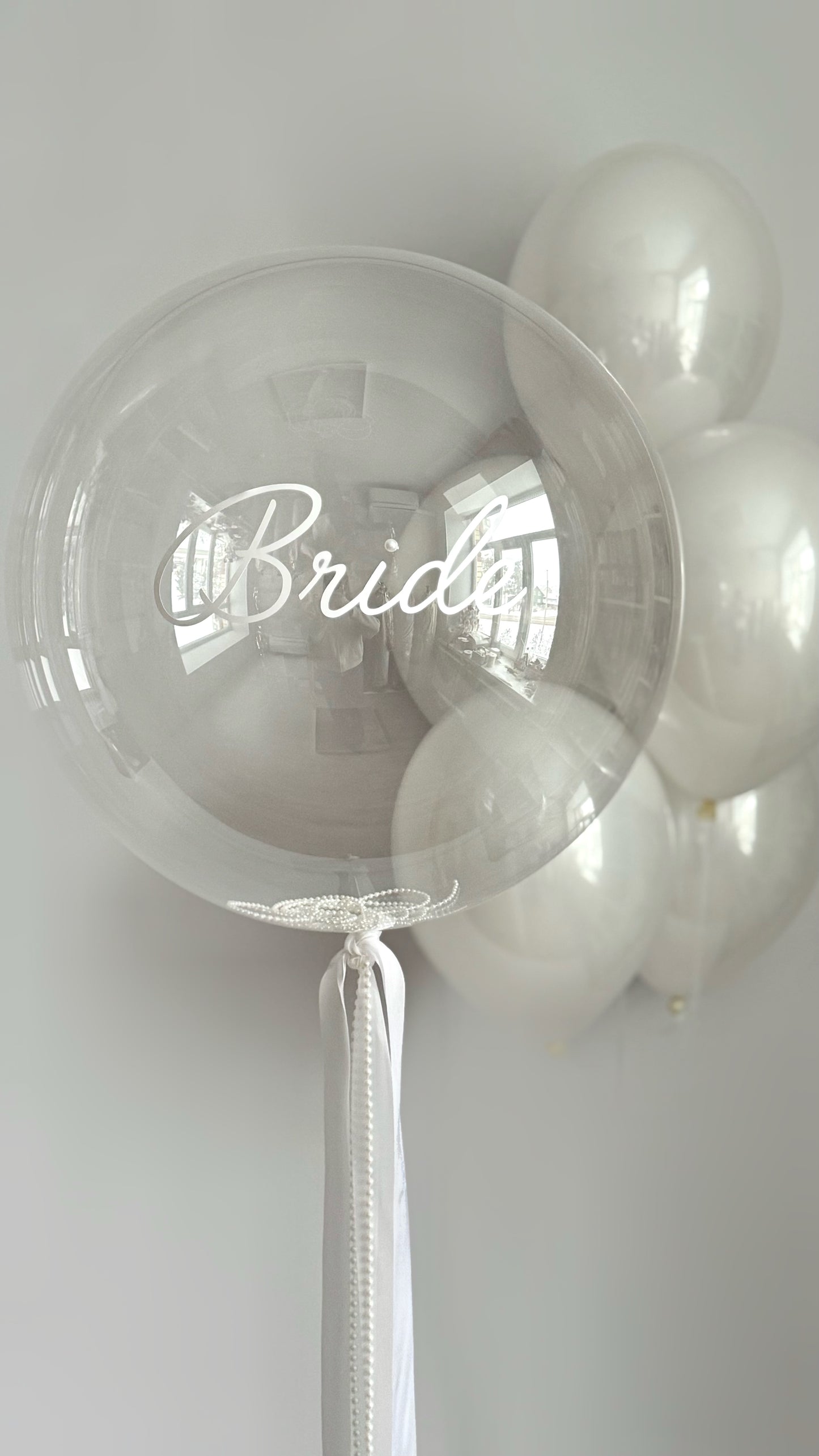 Clear bubble balloon with custom bridal sign and white side balloons for event decor in NYC