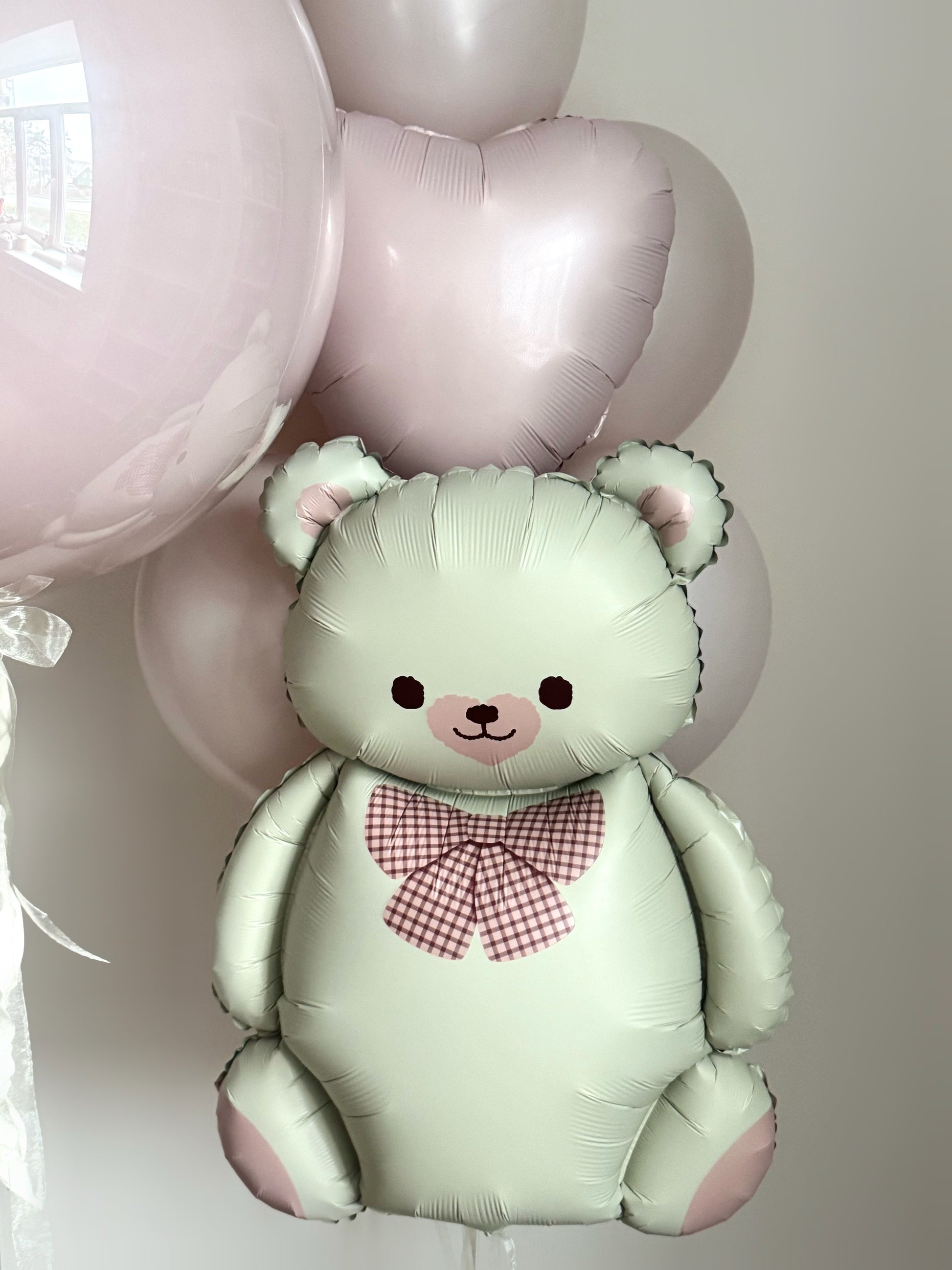 Close-up of teddy bear balloon with blush heart balloons for baby celebration decor in Brooklyn