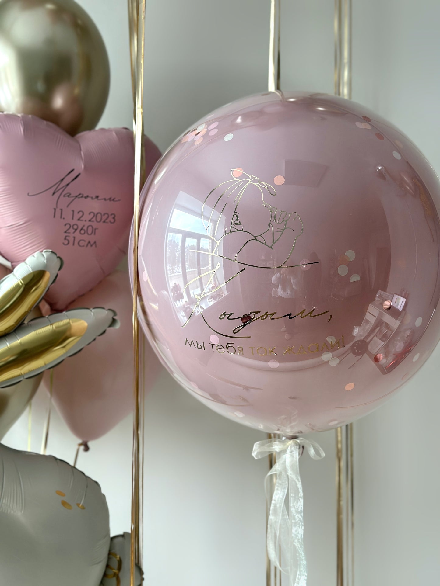 Close-up of personalized baby girl bubble balloon with soft pink and champagne balloons in Brooklyn