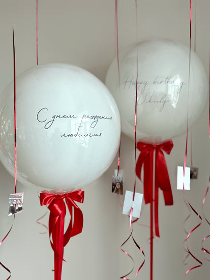 Close-up of personalized white double bubble balloon with red ribbons for celebration decor in Brooklyn