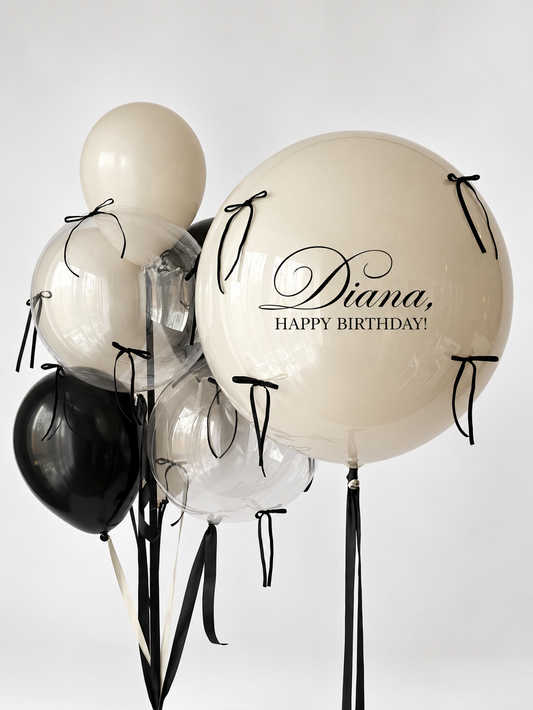 Large personalized cream bubble balloon with black bows, two smaller clear bubble balloons and coordinating black and cream balloons.