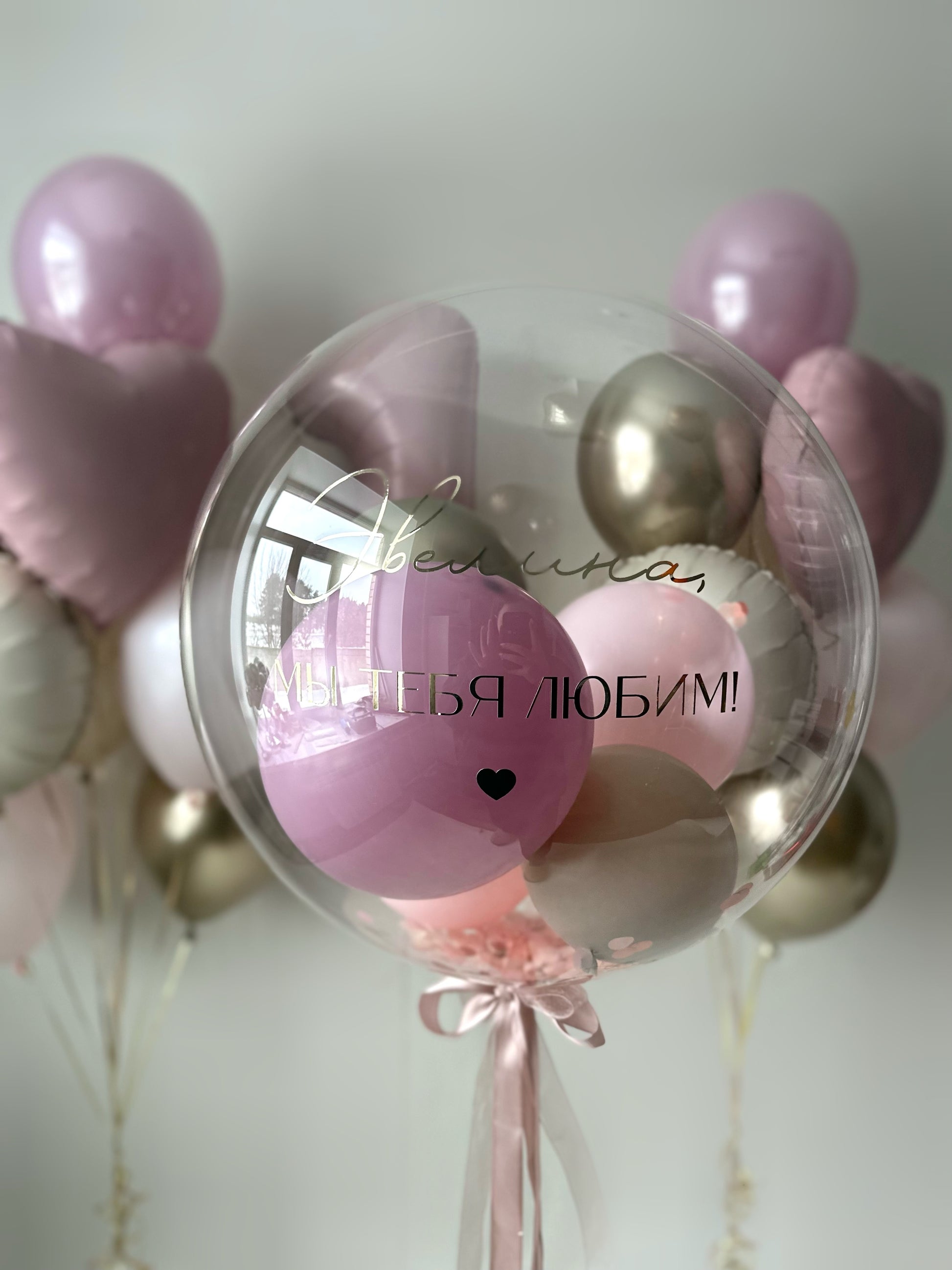 Close-up of custom bubble balloon with pink mini balloons and heart decor for birthday celebration in Brooklyn