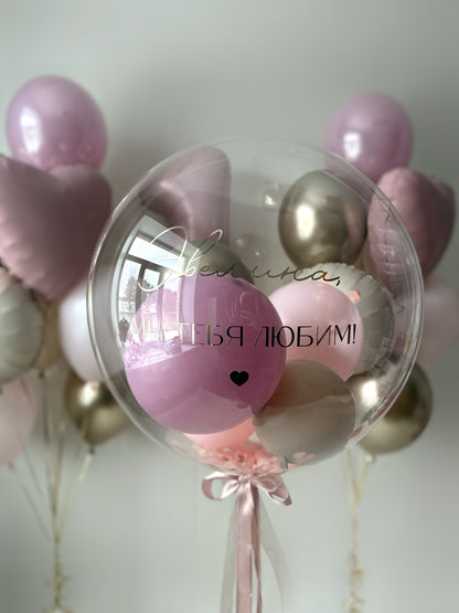 Close-up of custom bubble balloon with pink mini balloons and heart decor for birthday celebration in Brooklyn