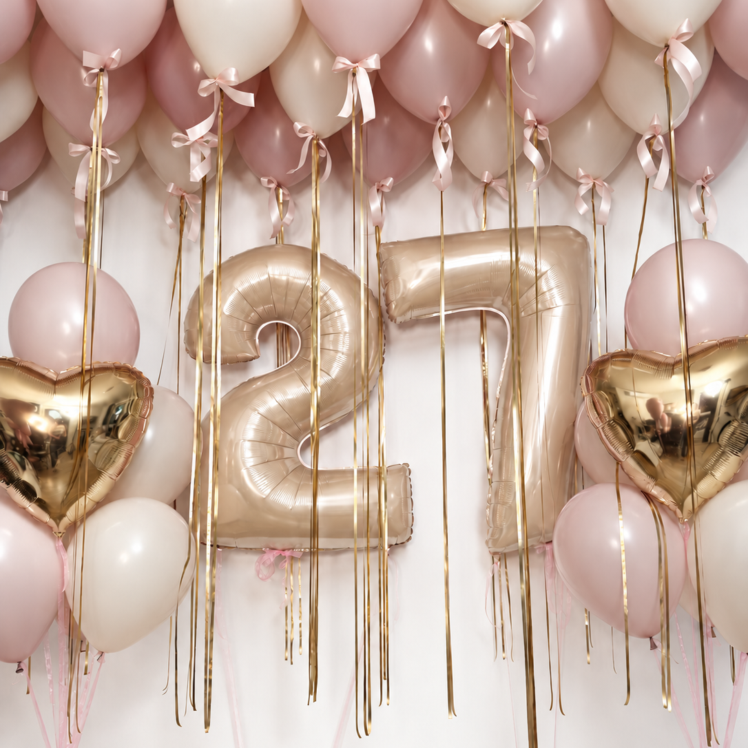 Golden blush birthday balloon set with gold number balloons, foil heart bouquets, and pink and ivory ceiling balloons finished with bows.