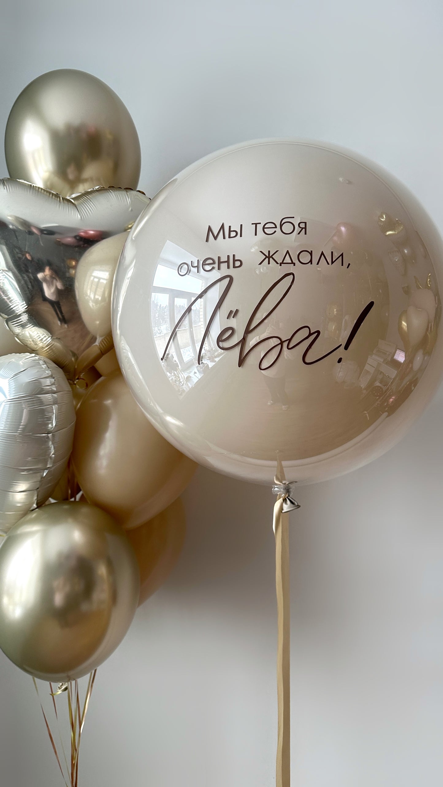 Close-up of golden welcome balloon set with custom sign bubble balloon and neutral gold styling in Brooklyn