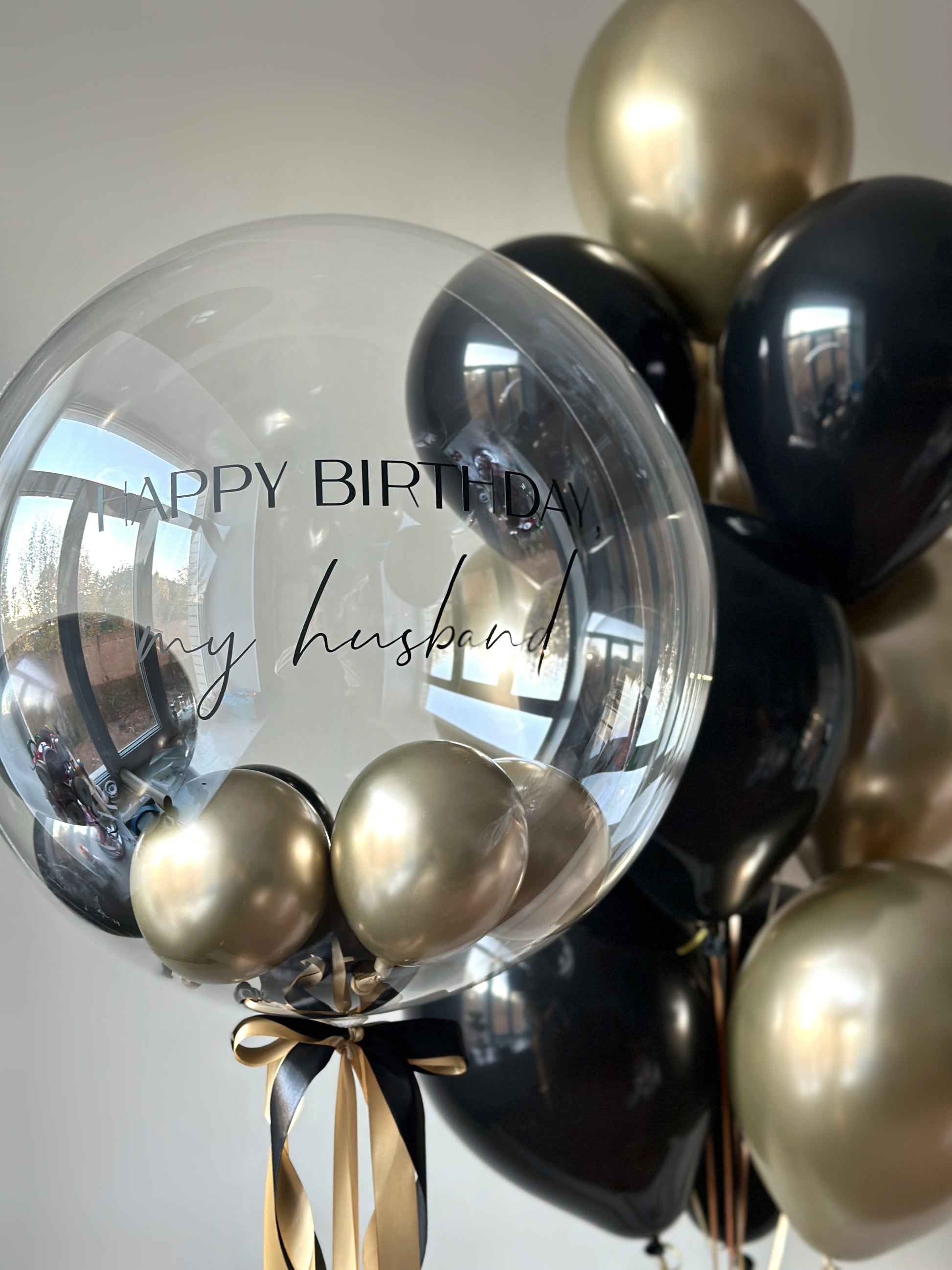 Close-up of personalized bubble balloon with black and gold balloons for husband birthday decor in Brooklyn
