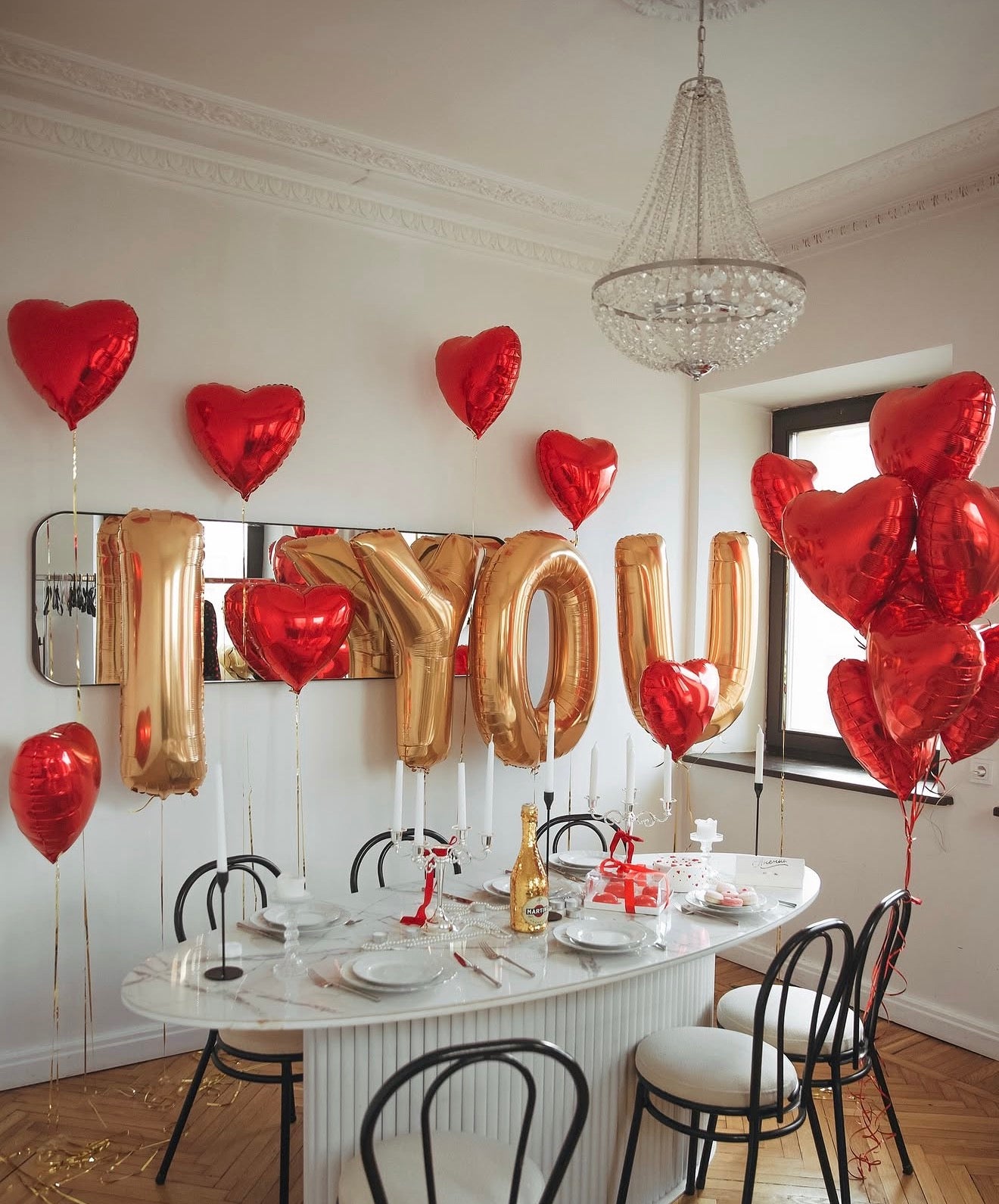 Romantic room decor with gold I YOU letter balloons, red heart balloons on individual weights, and a heart balloon bunch for a surprise celebration in New York