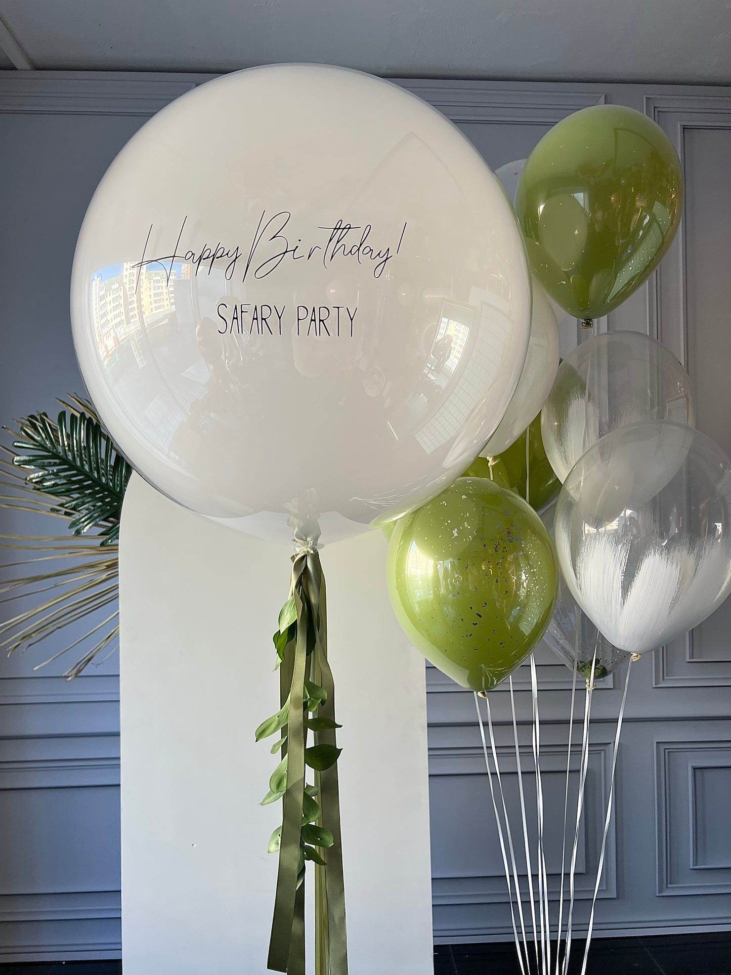 Jungle party balloon set with custom sign bubble balloon and green glass balloons for modern birthday decor in New York