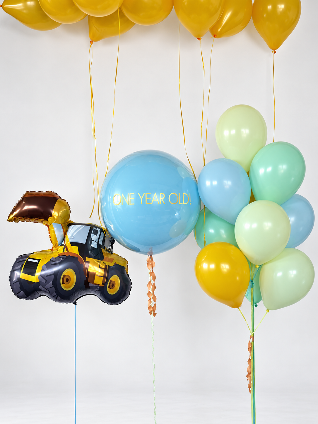 Yellow construction loader balloon with a personalized blue bubble, a bunch of blue, mint and yellow balloons, and yellow ceiling balloons.