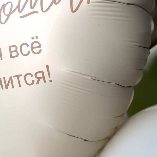 Close-up of matte heart foil balloon with printed message and neutral sage balloon styling
