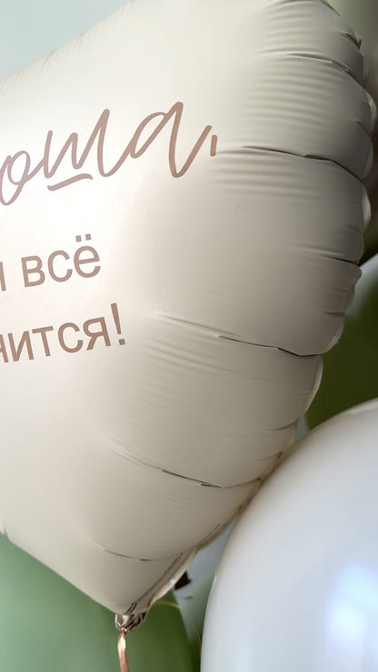 Close-up of matte heart foil balloon with printed message and neutral sage balloon styling