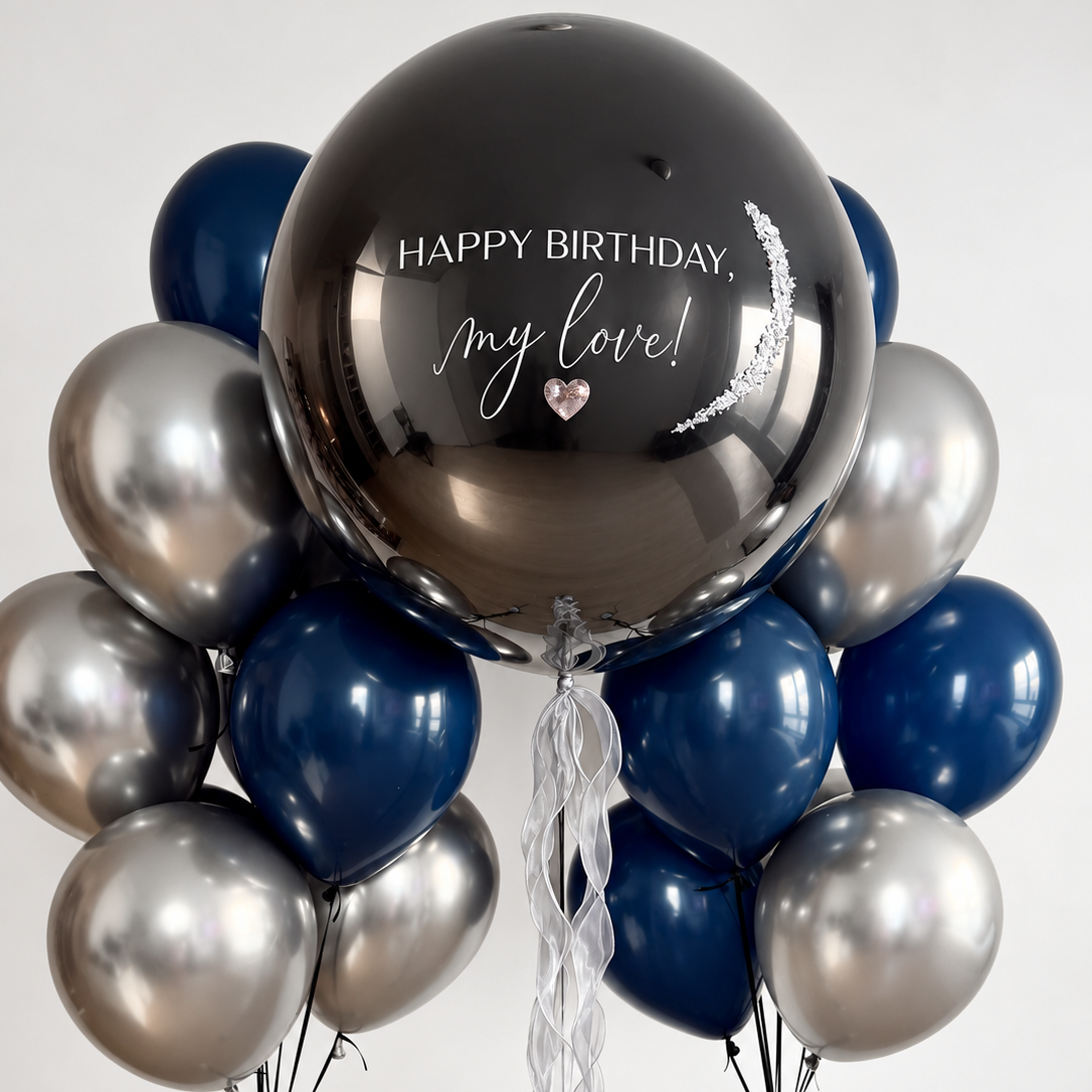 Dark personalized bubble balloon with white birthday lettering and silver accents, flanked by two bunches of navy blue and metallic silver balloons.