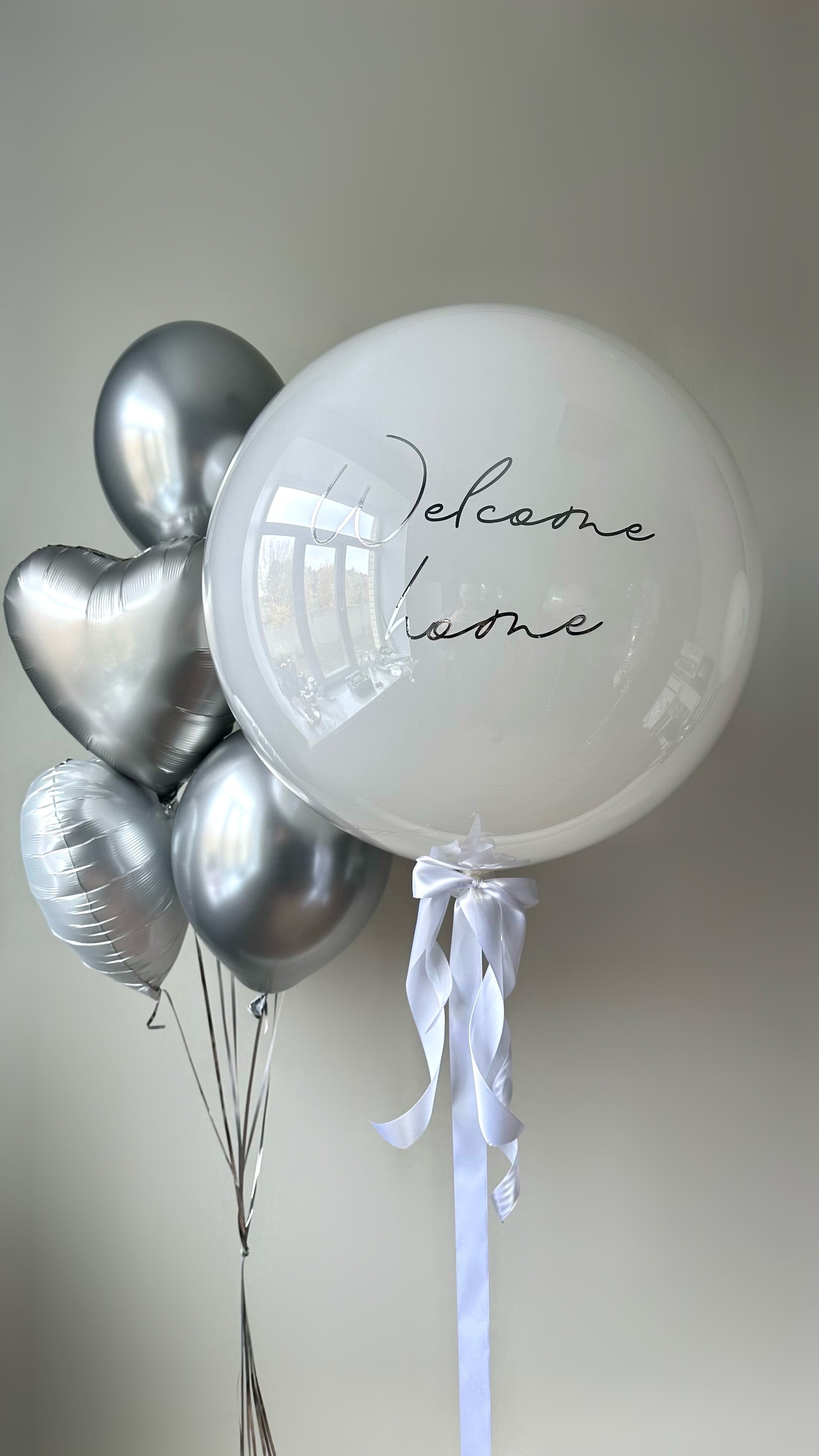 Simple welcome balloon set with custom sign bubble balloon and silver heart balloons for baby celebration decor in New York