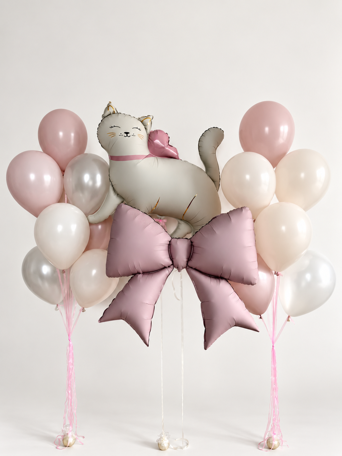 White cat balloon above a large dusty pink bow, with two bunches of pink, ivory and silver balloons and pink ribbons.